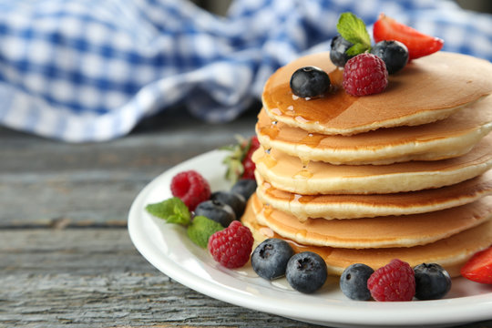 Delicious pancakes with berries on blue wooden background