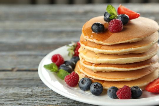 Delicious pancakes with berries on blue wooden background