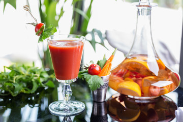 bright summer refreshing alcoholic cocktail Bloody Mary on a table in a restaurant with a creative decoration of cherry pepper greens. soft focus