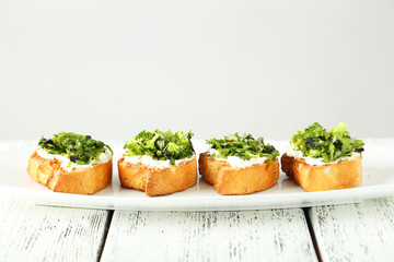 Tasty fresh bruschetta on plate on white wooden background