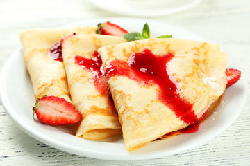 Pancakes with strawberry on plate on white wooden backgound