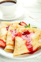 Pancakes with strawberry on plate on white wooden backgound