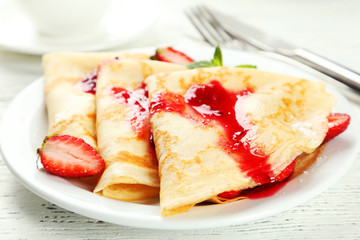 Pancakes with strawberry on plate on white wooden backgound
