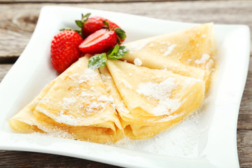 Pancakes with strawberry on plate on grey wooden backgound