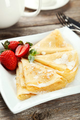 Pancakes with strawberry on plate on grey wooden backgound