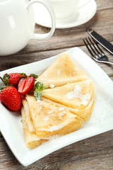 Pancakes with strawberry on plate on grey wooden backgound