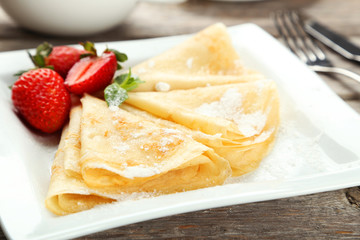 Pancakes with strawberry on plate on grey wooden backgound