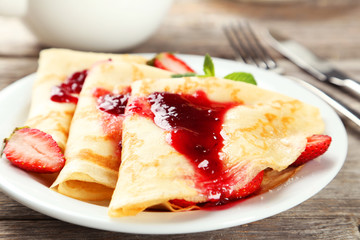 Pancakes with strawberry on plate on grey wooden backgound