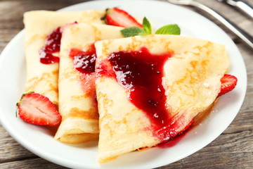 Pancakes with strawberry on plate on grey wooden backgound