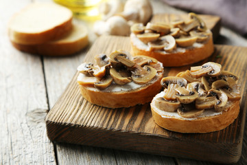 Tasty fresh bruschetta with mushrooms on cutting board on grey w