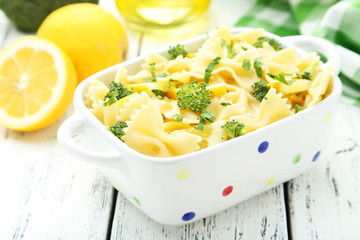 Delicious pasta with with broccoli in bowl on white wooden backg