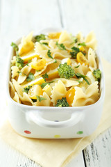 Delicious pasta with with broccoli in bowl on white wooden backg