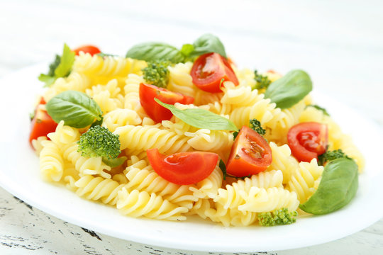 Delicious pasta on plate on white wooden background