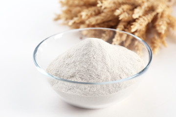 Glass bowl with flour and ears isolated on white