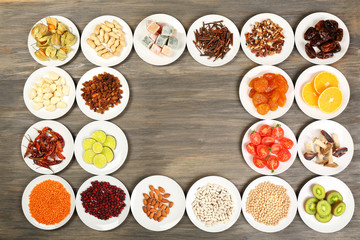 Different products on saucers on wooden table, top view