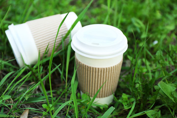 Paper cups on green grass background