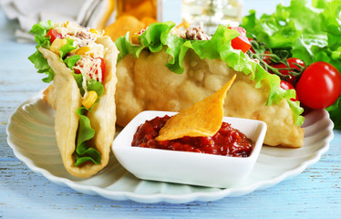 Tasty taco with tomato dip on plate and vegetables on table close up