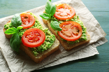 Vegan sandwich with avocado and vegetables on wooden background