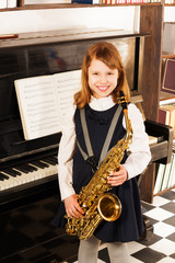 Smiling girl in school uniform with alto saxophone