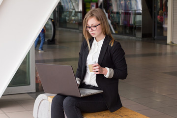 Young business woman with a laptop drinking coffee