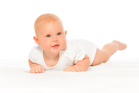 Baby with cheeks in white bodysuit laying alone
