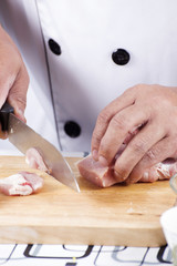 Chef cutting raw pork on wooden board
