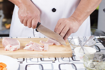 Obraz na płótnie Canvas Close up of Hand's Chef cutting raw pork on wooden board