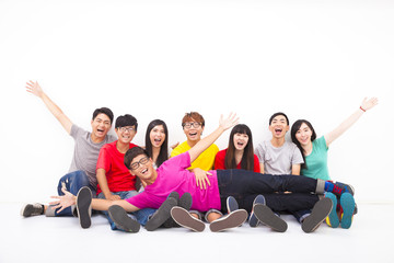 Happy young group sitting together against white wall