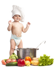 Little boy in chef's hat playing with casserole and vegetables