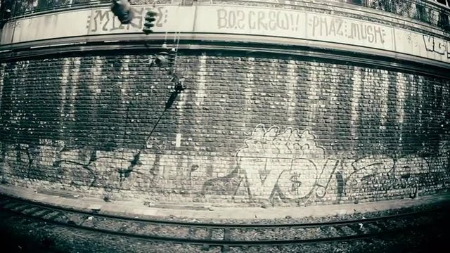 Train approaching Paris St.Lazare st.  pan of tracks, brick wall, graffiti.