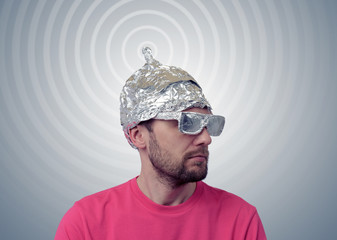 Bearded funny man in a cap of aluminum foil sends signals - obrazy, fototapety, plakaty