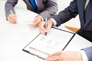 Two businessmen looking at report and having a discussion in off