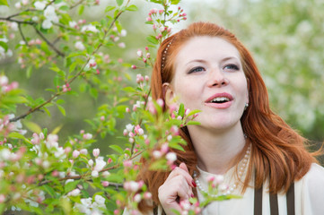 Fototapeta premium beautiful red-haired girl walks in apple orchard