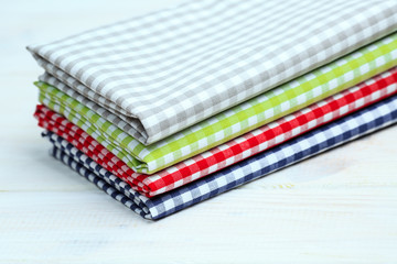 Multi-colored kitchen towels, on a white wooden background