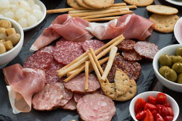 Assorted meat snacks, sausages and pickles on a blackboard