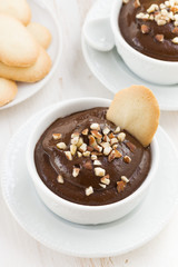 chocolate mousse with biscuits and nuts in white cups, vertical