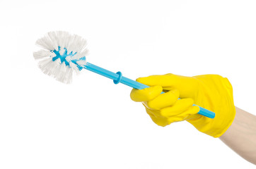 human hand holding a blue toilet brush in yellow gloves
