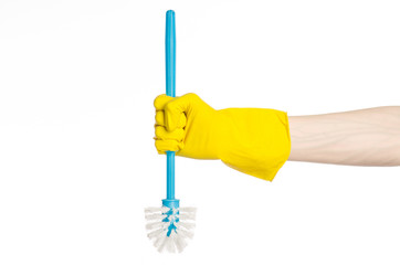 human hand holding a blue toilet brush in yellow gloves