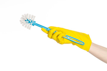 human hand holding a blue toilet brush in yellow gloves