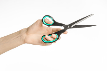 human hand holding a black scissors with blue accents in studio
