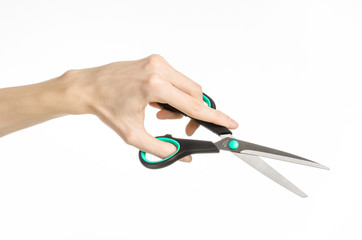 human hand holding a black scissors with blue accents in studio