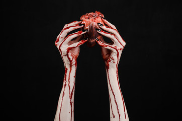 bloody hands with black nails holding bloody human heart