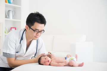 Good looking asian doctor and newborn baby on the clinic