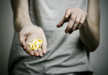 addict holding a narcotic pills on a dark background