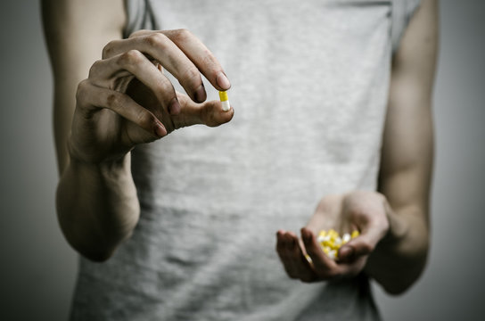 addict holding a narcotic pills on a dark background