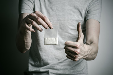 addict holding package of cocaine in a gray shirt  in the studio
