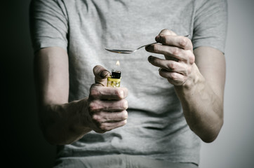 addict holding spoon lighter and heats the liquid drug