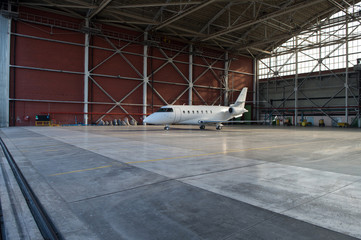 Business jet airplane is in hangar. - obrazy, fototapety, plakaty
