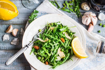 light green salad with arugula, cheese, almonds, lemon and olive