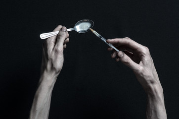 hand addict lies on a dark table and around it are drugs